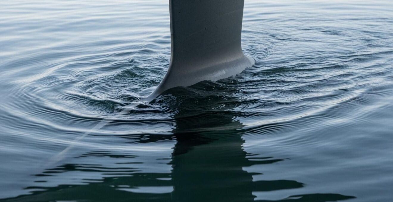 Photographie macro détaillée d'un appendice de bateau (dérive ou safran) immergé avec des flux d'eau visibles